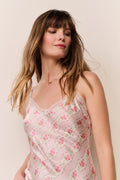 Woman wearing a light pink floral sleeveless top against a beige background
