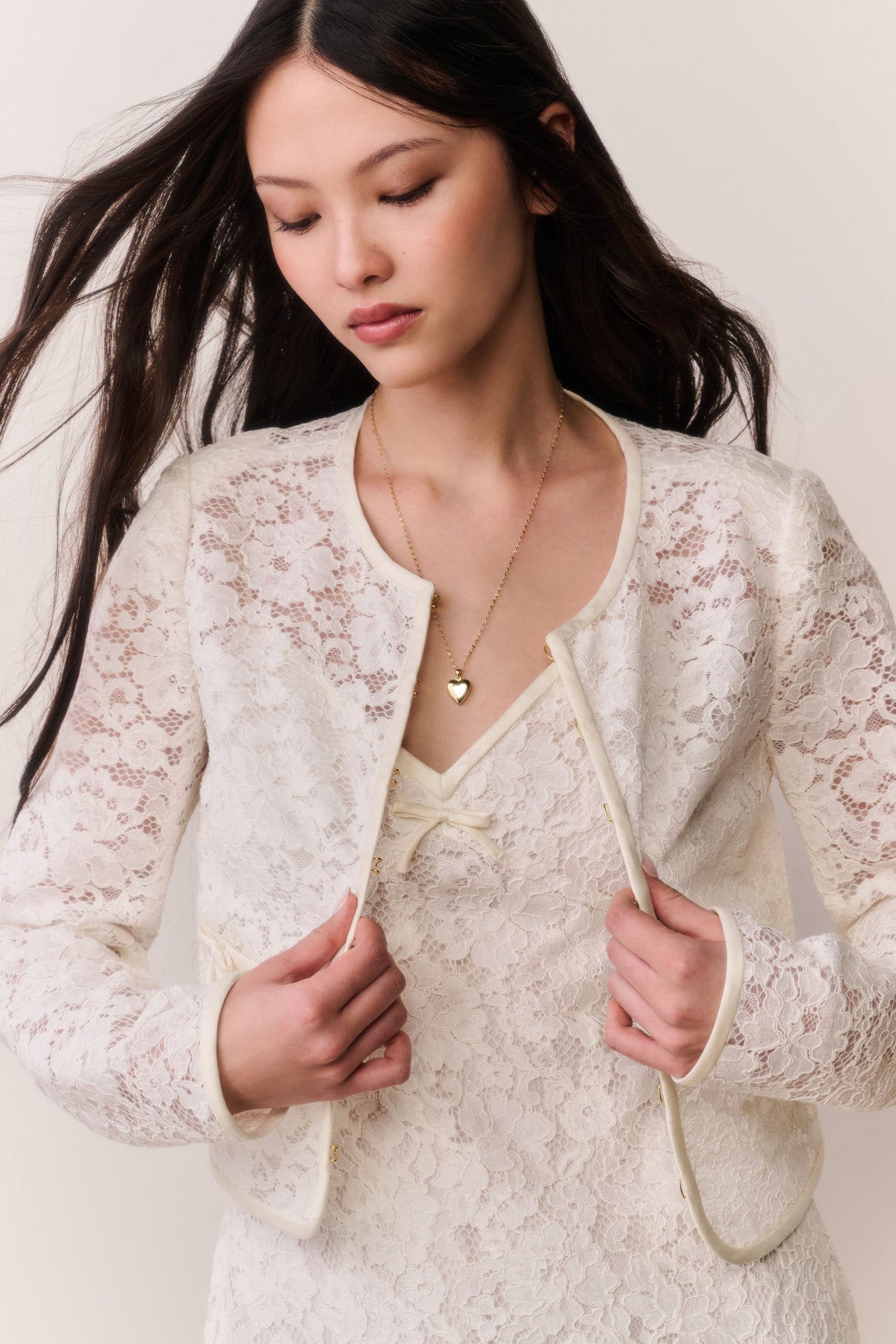 Ivory lace cropped jacket with long sleeves, front zipper, scalloped patch pockets