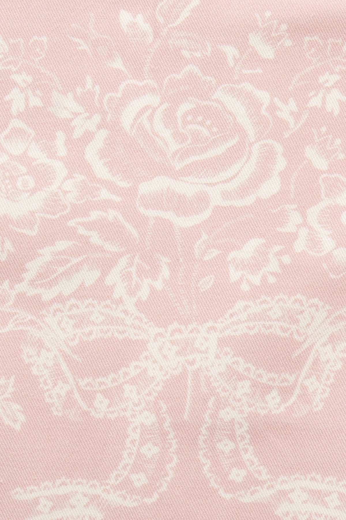 Close-up of perennial pink fabric with white floral and scroll pattern