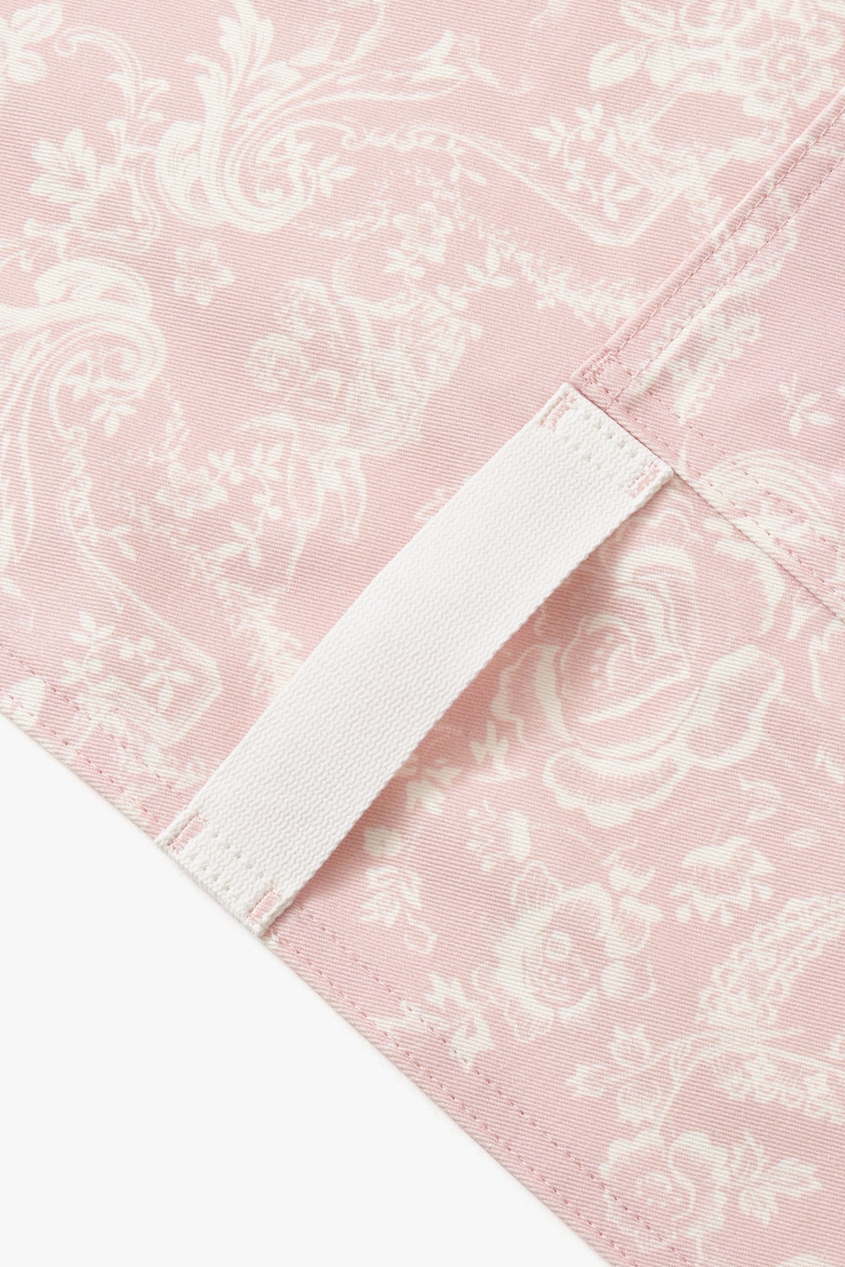 Close-up of pink apron panel with white contrast binding along diagonal edge