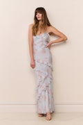 Woman wearing a light blue floral dress against a beige wall