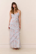 Woman wearing a light blue floral dress against a beige wall