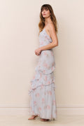 Woman wearing a light blue floral dress against a beige wall