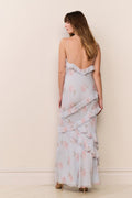 Woman wearing a light blue floral dress against a beige wall