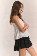 Black tiered ruffle mini skirt in side view with gathered waist and layered hem
