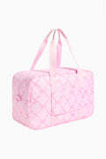Pink quilted duffle bag with long ribbon handles and crosshatch pattern