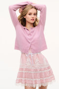 Pink lace mini dress under cropped cardigan, tiered ruffle skirt visible