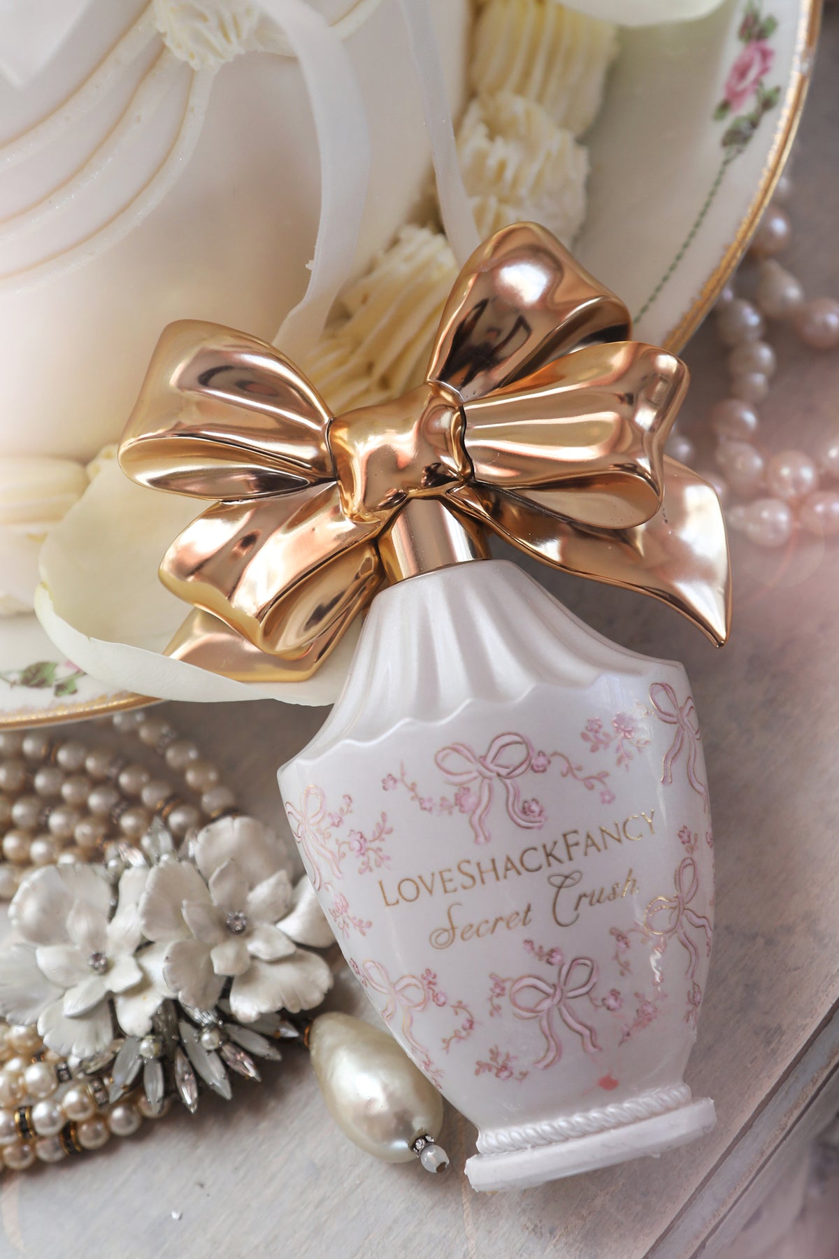 Eau de parfum bottle close-up with gold bow, pearls, and creamy rose decor