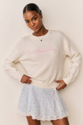 Cream cotton pullover with pink embroidered script and ribbed hem and cuffs