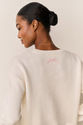 Cream cotton pullover with ribbed crew neck and pink embroidered back logo