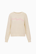 Cream cotton pullover with crew neck, ribbed cuffs, and pink embroidered script