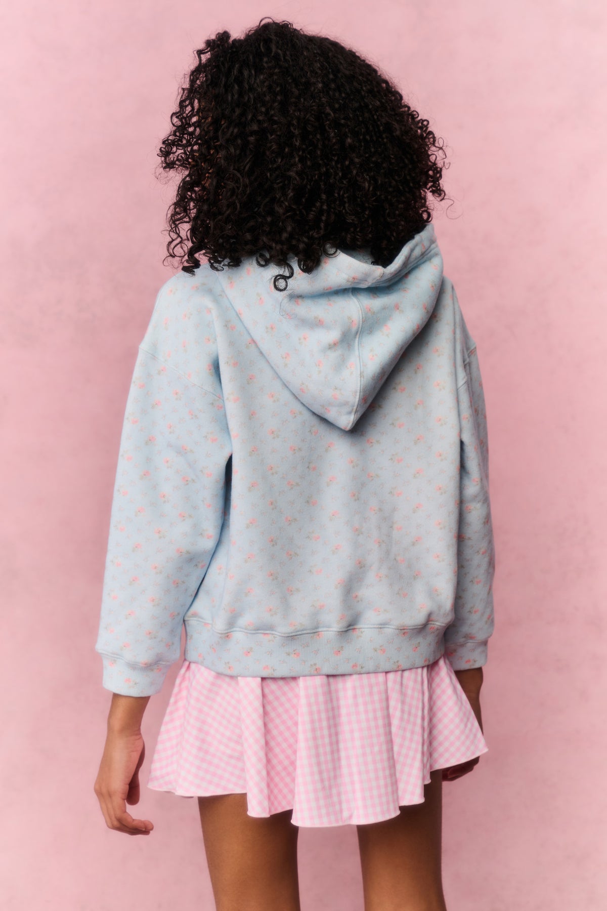 Pink gingham skort with pleated flared hem, shown under a light blue hoodie