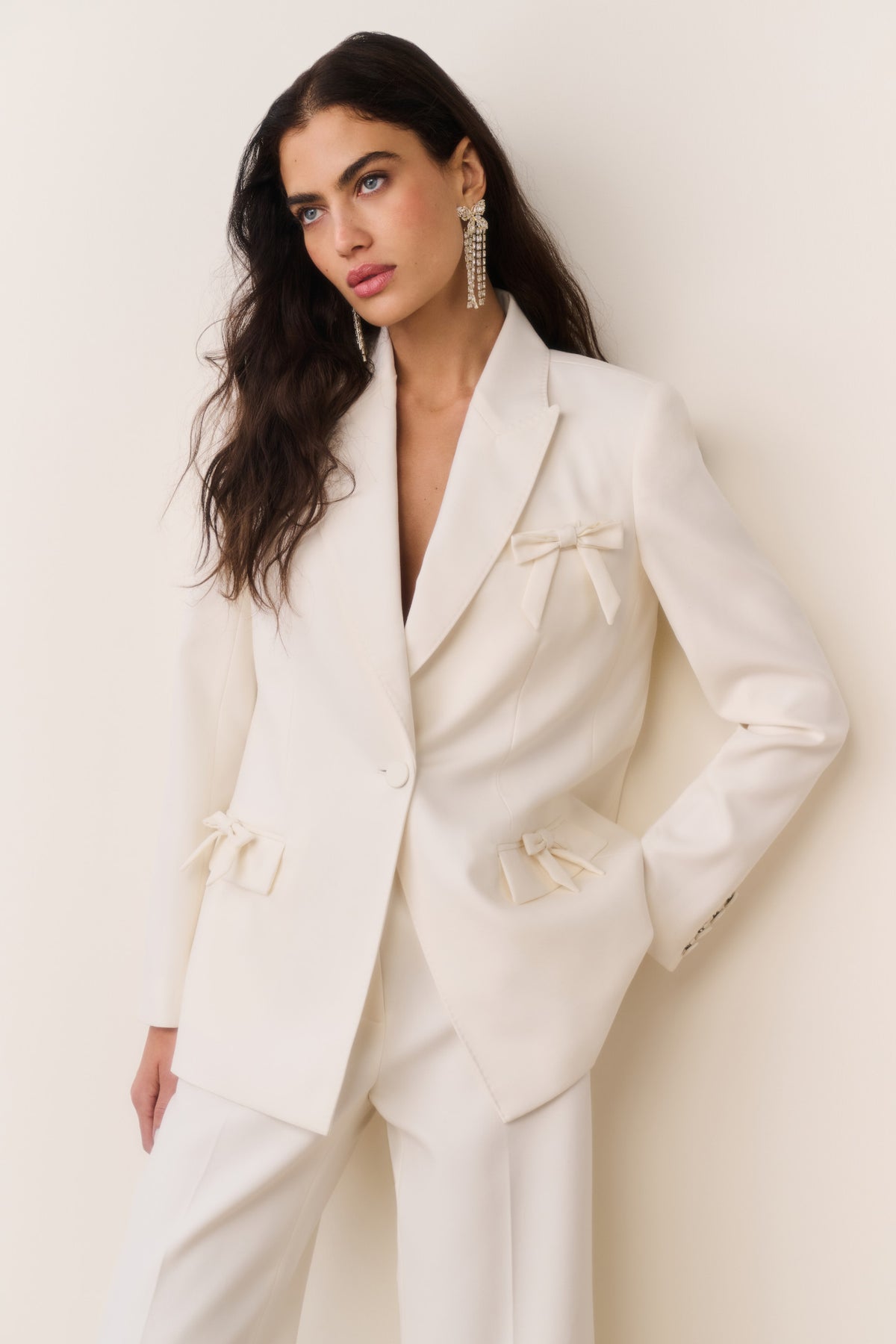 Cream wool-blend blazer with satin bows at chest and flap pockets, front button closure