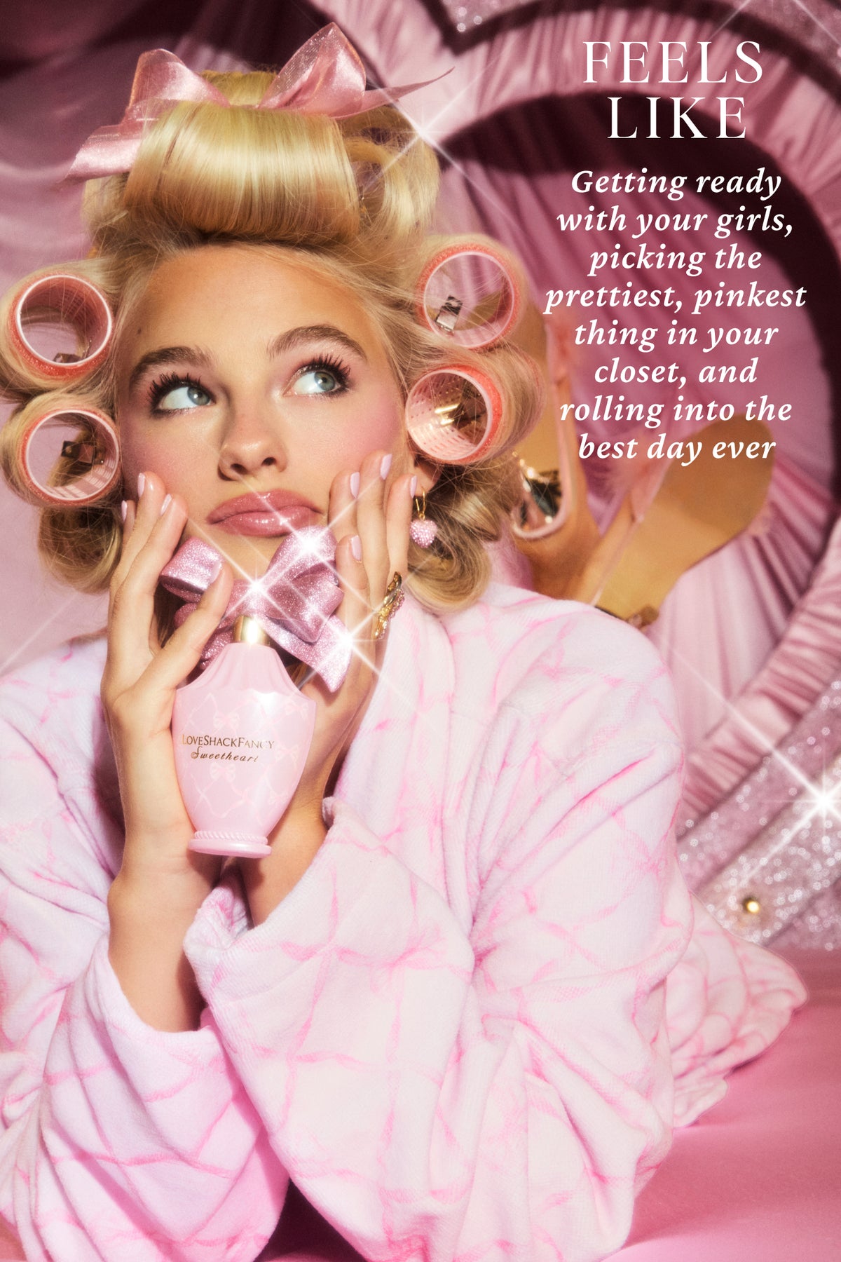 Pink robe model holding a Sweetheart Eau de Parfum bottle