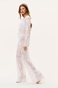 White lace cover-up pants with wide legs, sheer fabric and allover floral print, side view