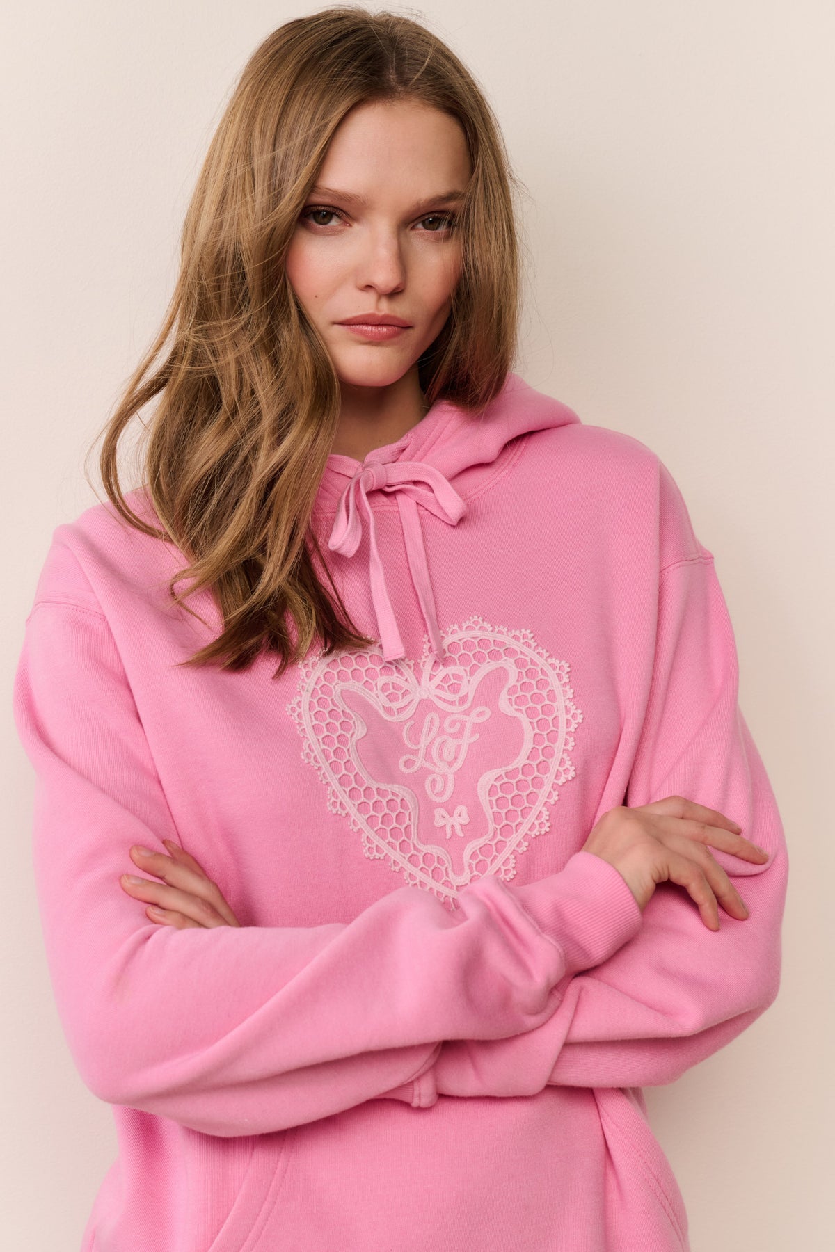 Pink fleece hoodie with heart lace-style applique, front pouch pocket, drawstring hood