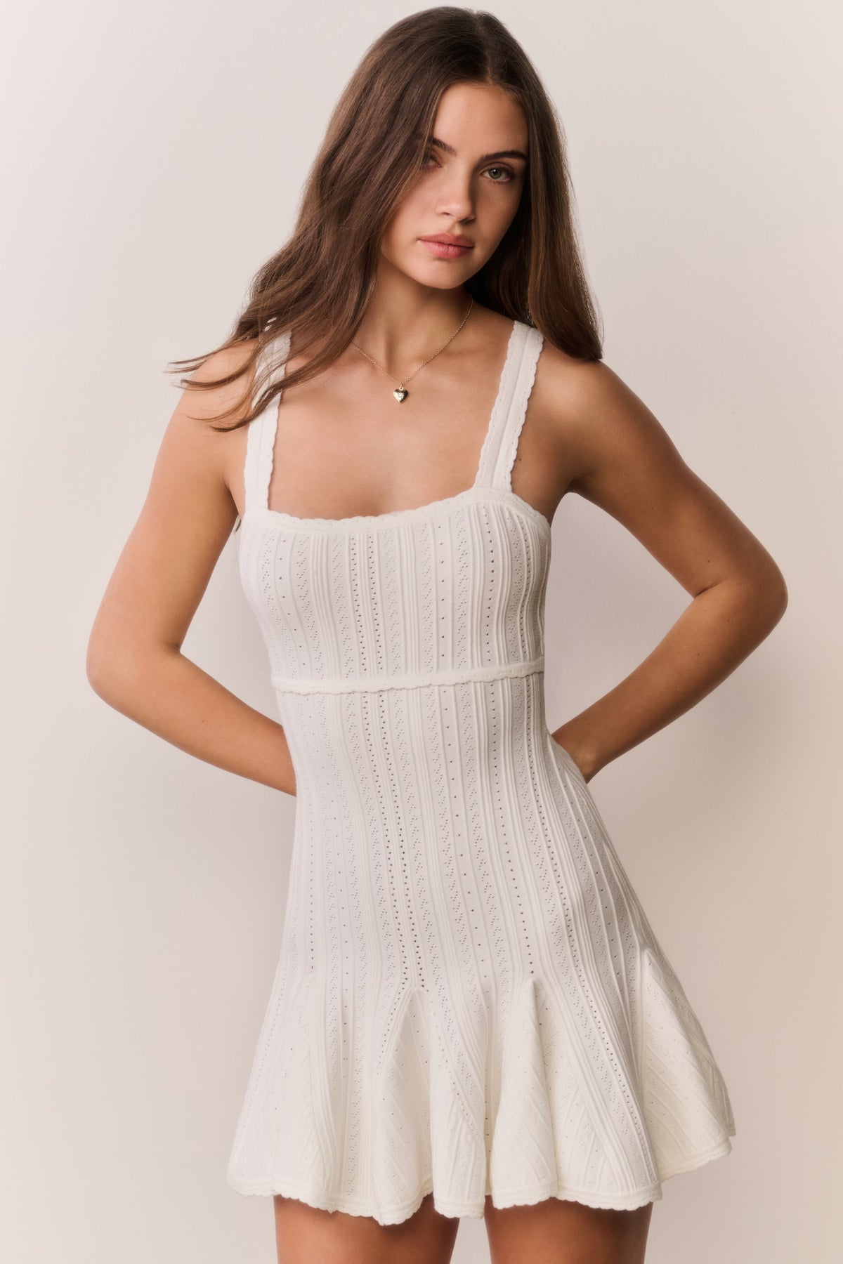 White pointelle mini dress on model, square neck and sleeveless flared hem