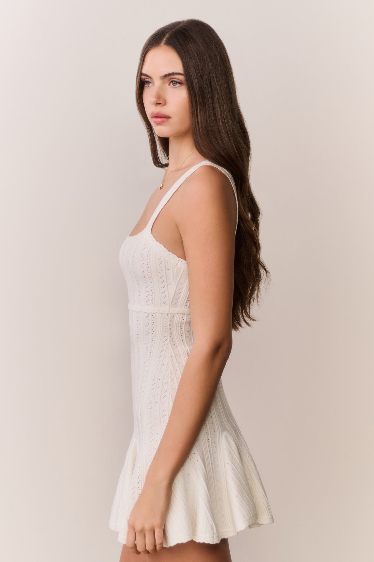 White pointelle mini dress with square neckline, sleeveless bodice, and flared skirt