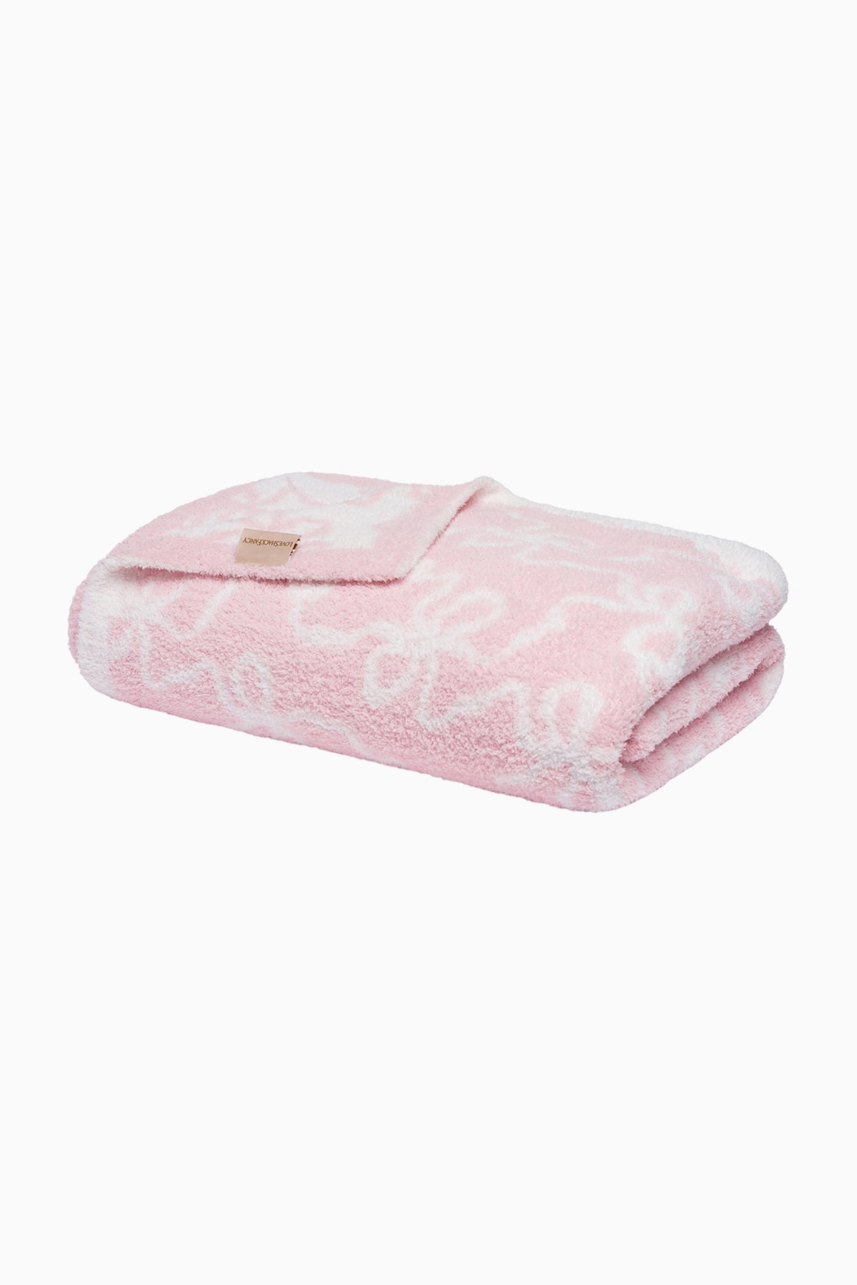 Pastel pink teddy bow blanket, folded with white floral-like pattern and small tag