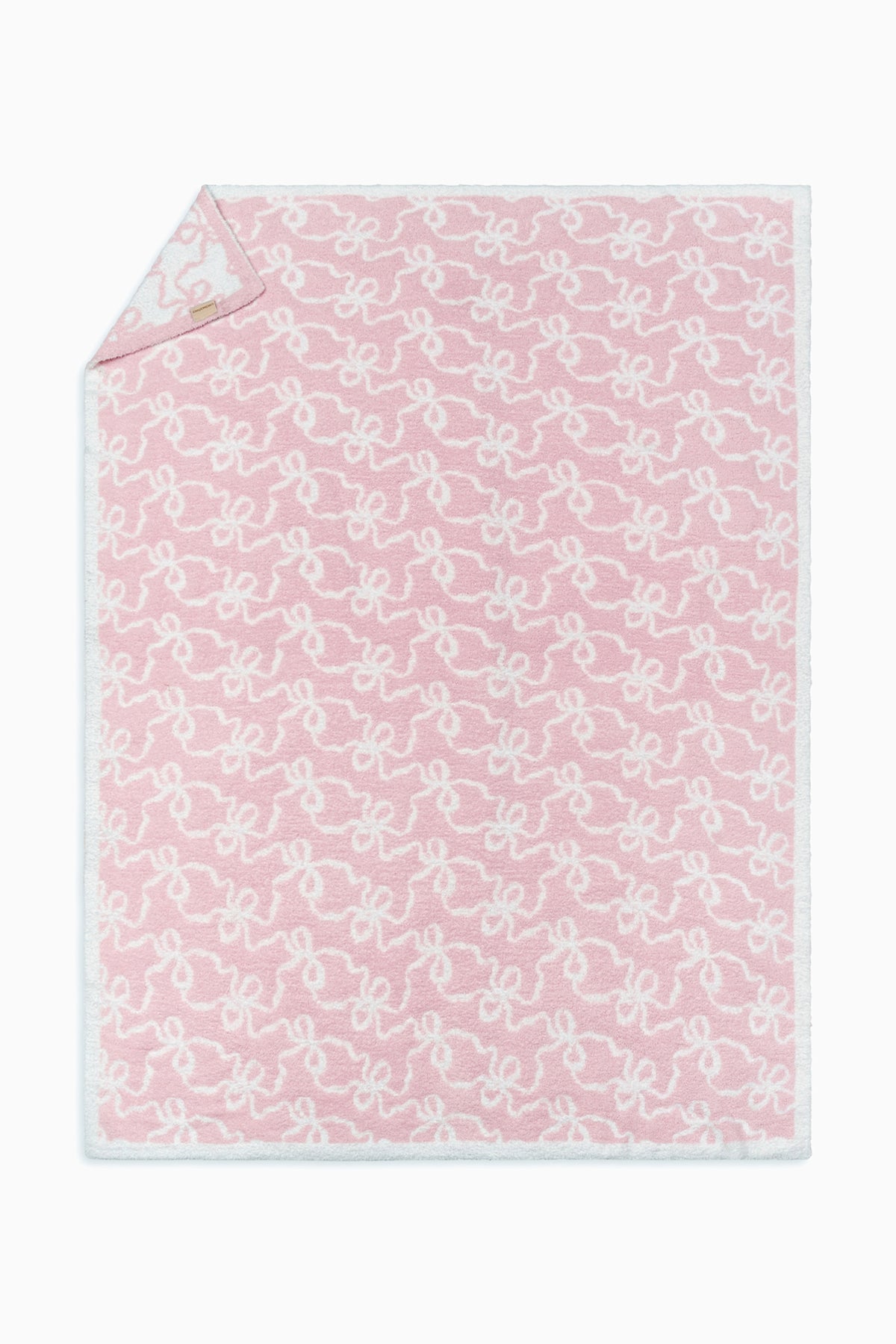 Pastel pink teddy bow blanket with allover white bow pattern and stitched edge