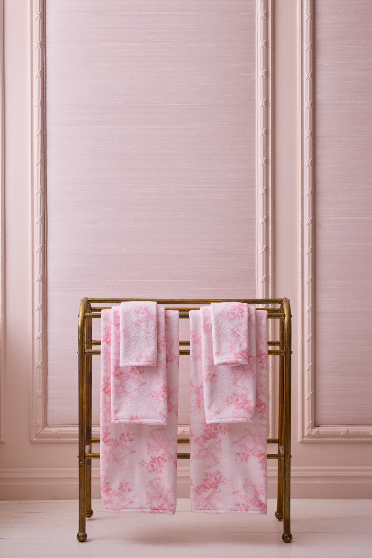 Pink cotton wash cloths folded on a gold rack
