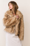 Faux fur jacket in burnt caramel, close-up with plush shaggy texture and open neckline.