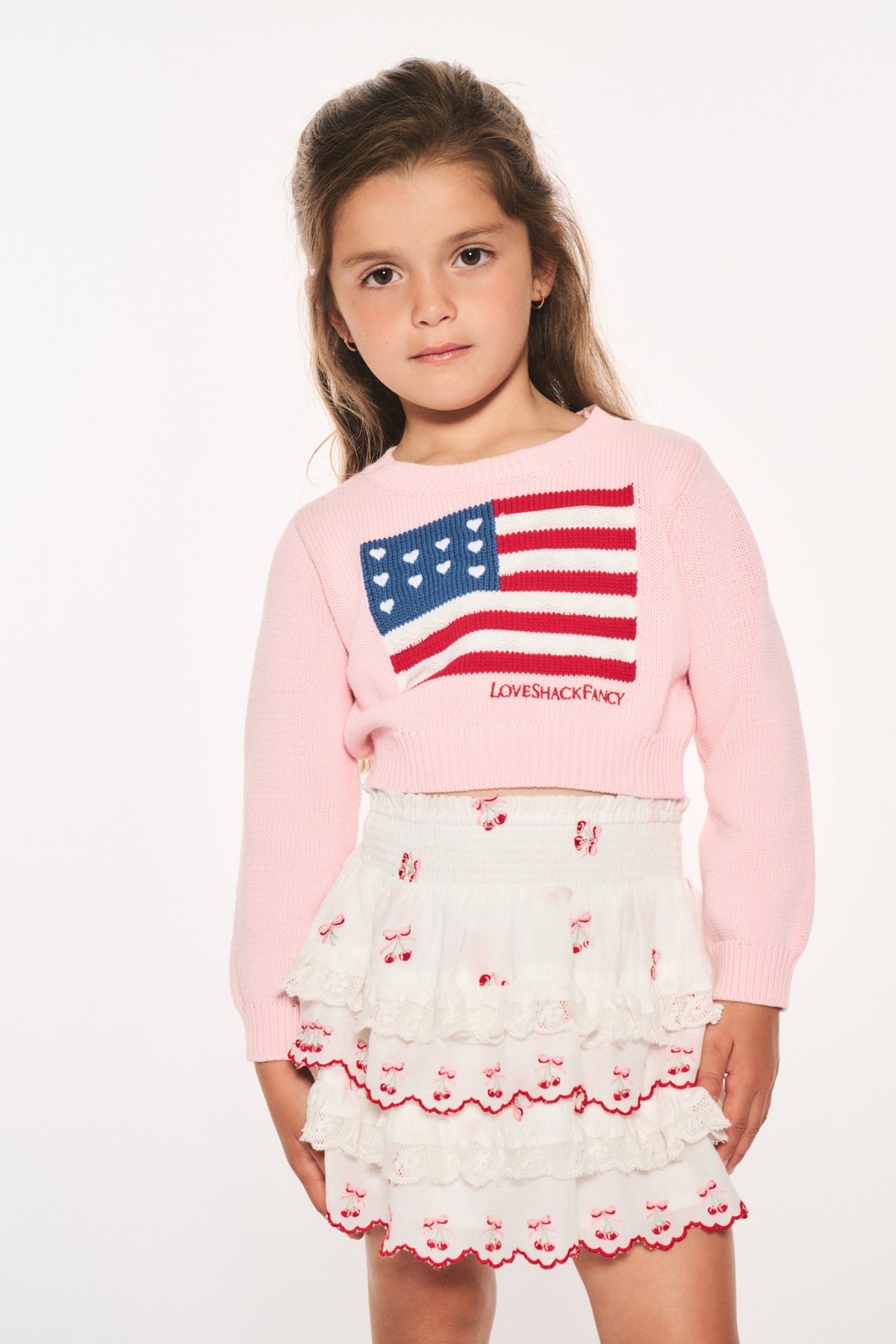 Girls' pink knit flag pullover featuring a red, white, and blue flag patch on front