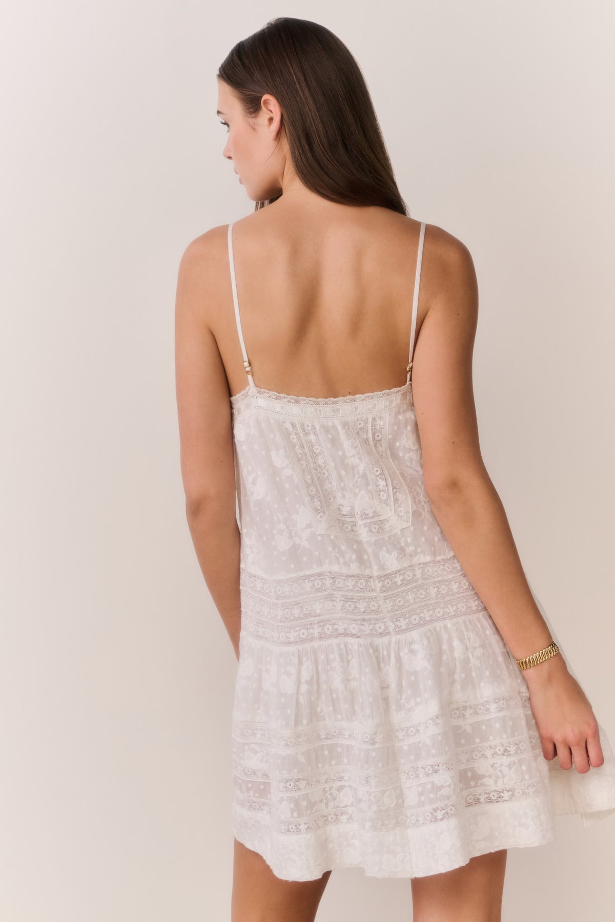 White Victorian-style mini dress with thin straps and lace-covered back panel