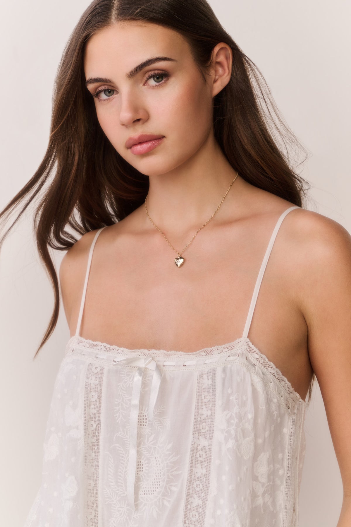 White mini sundress with thin spaghetti straps, lace bodice, and gathered bust