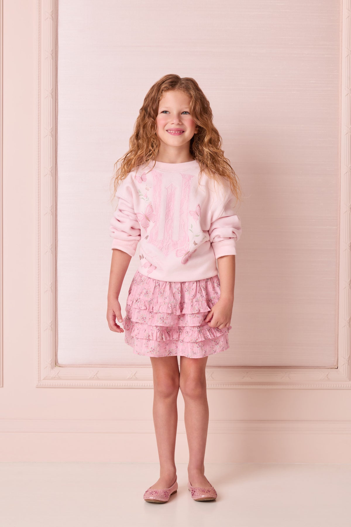 Light pink sweatshirt with long sleeves and butterfly graphic print at the front