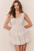 White sleeveless mini dress with lace-trim ruffles and vertical button details