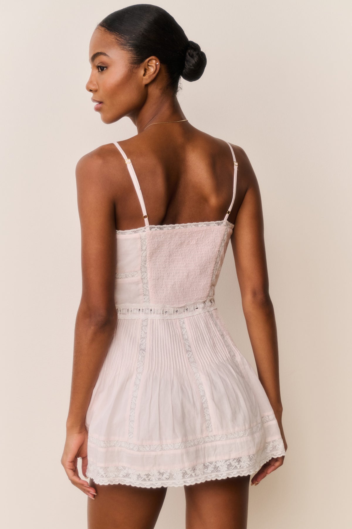 Pink cotton mini dress with lace trim, spaghetti straps, and tiered skirt