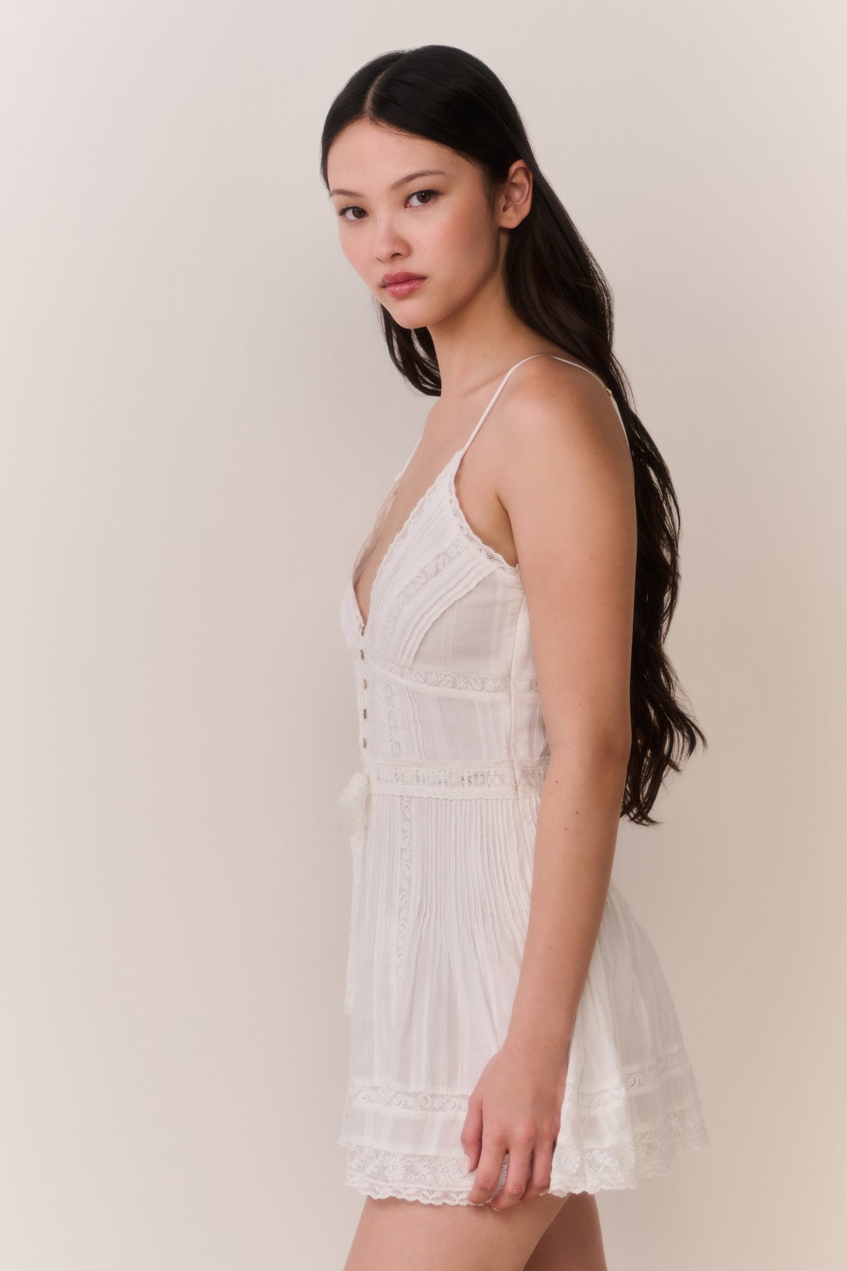 White cotton mini dress, lace-trimmed spaghetti straps, button front detail, side view