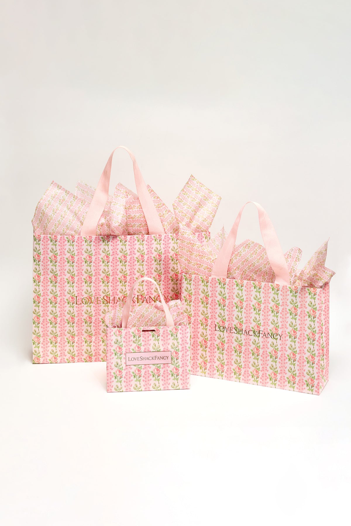 Pink patterned gift bags set with ribbon handles and a small matching tote
