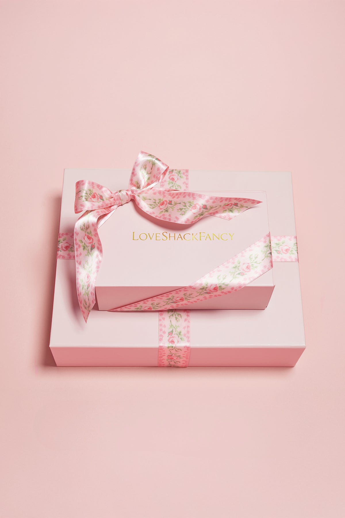 Pink gift packaging box with floral ribbon bow and attached gift tag