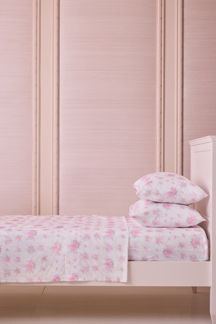 Pink floral sheet set with two folded pillow shams on a bed