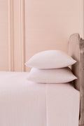 Printed cotton sheet set, pale pink micro-dot print, with stacked pillowcases and top sheet