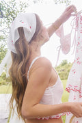 White embroidered napkin with small pink motif, lace-trim edge
