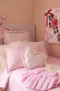 Heart-shaped ruffle pillow set on bed, light pink with layered ruffles