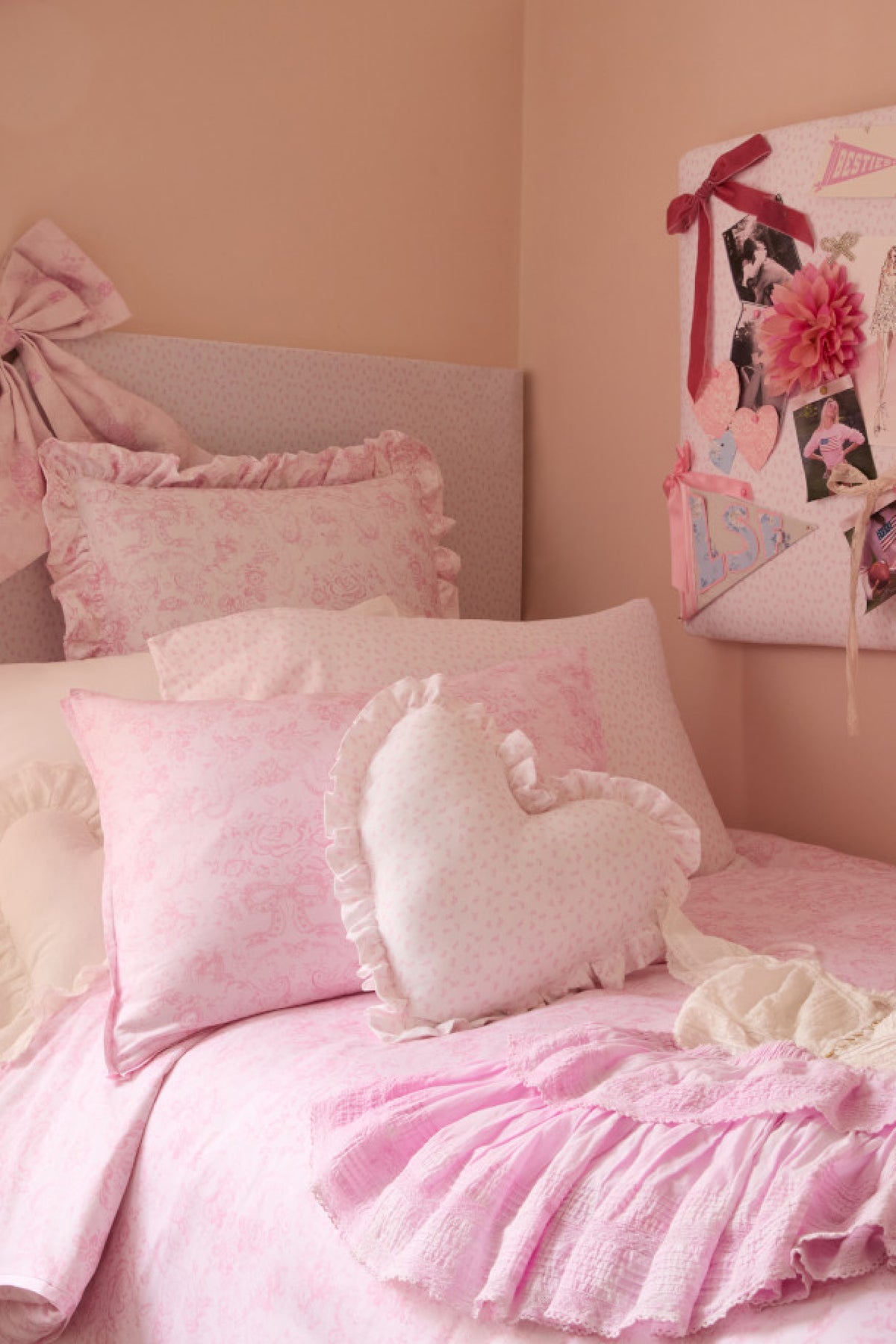 Heart-shaped ruffle pillow set on bed, light pink with layered ruffles