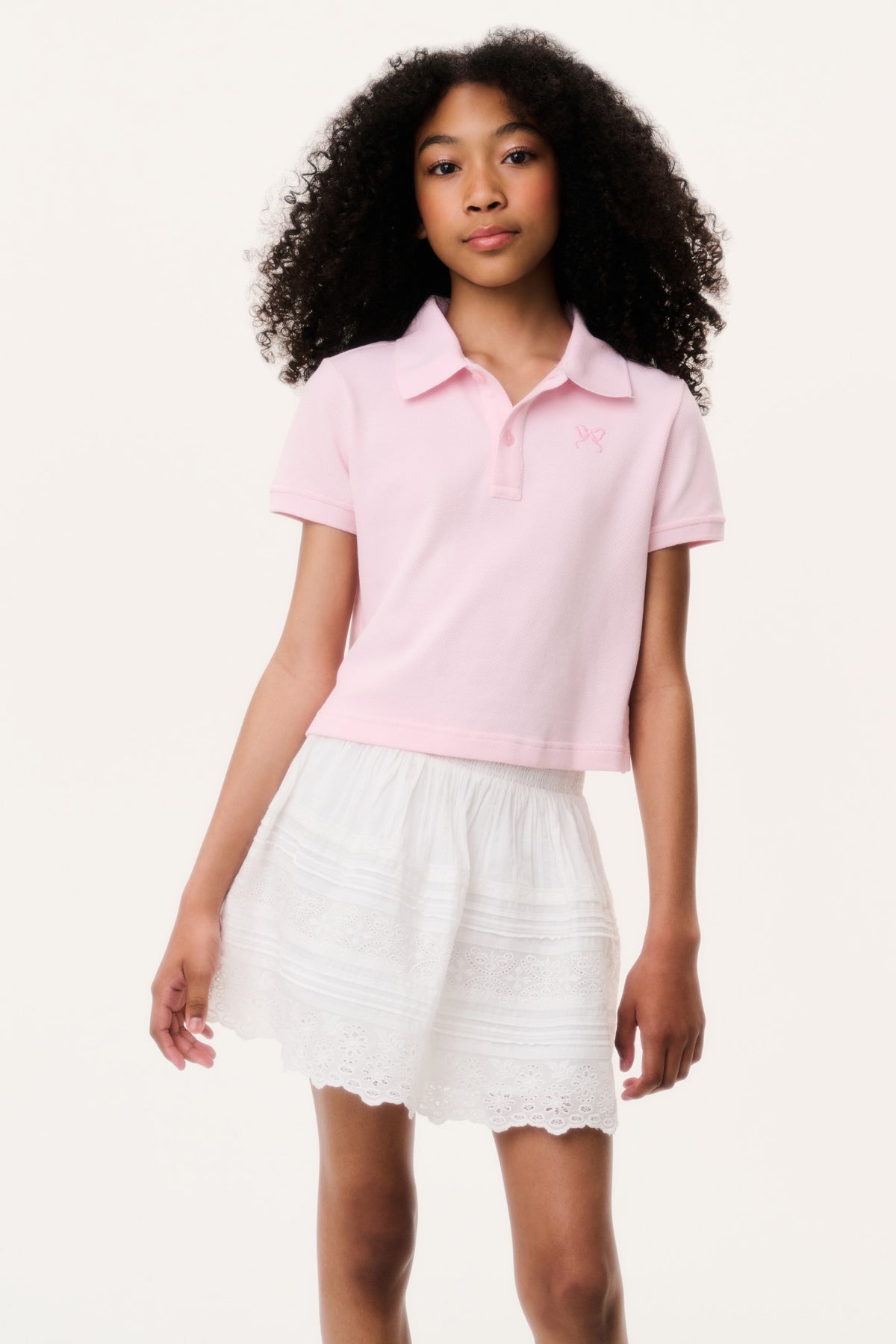 Light pink short-sleeve polo shirt with collar, paired with white tiered skirt