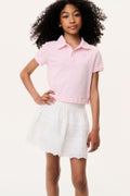 Light pink polo shirt with button placket and collar, worn with white tiered skirt