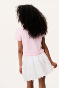 Light pink polo shirt back view with short sleeves, paired with white tiered skirt