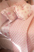 Soft pink quilt with diamond quilting and scattered floral pillow covers