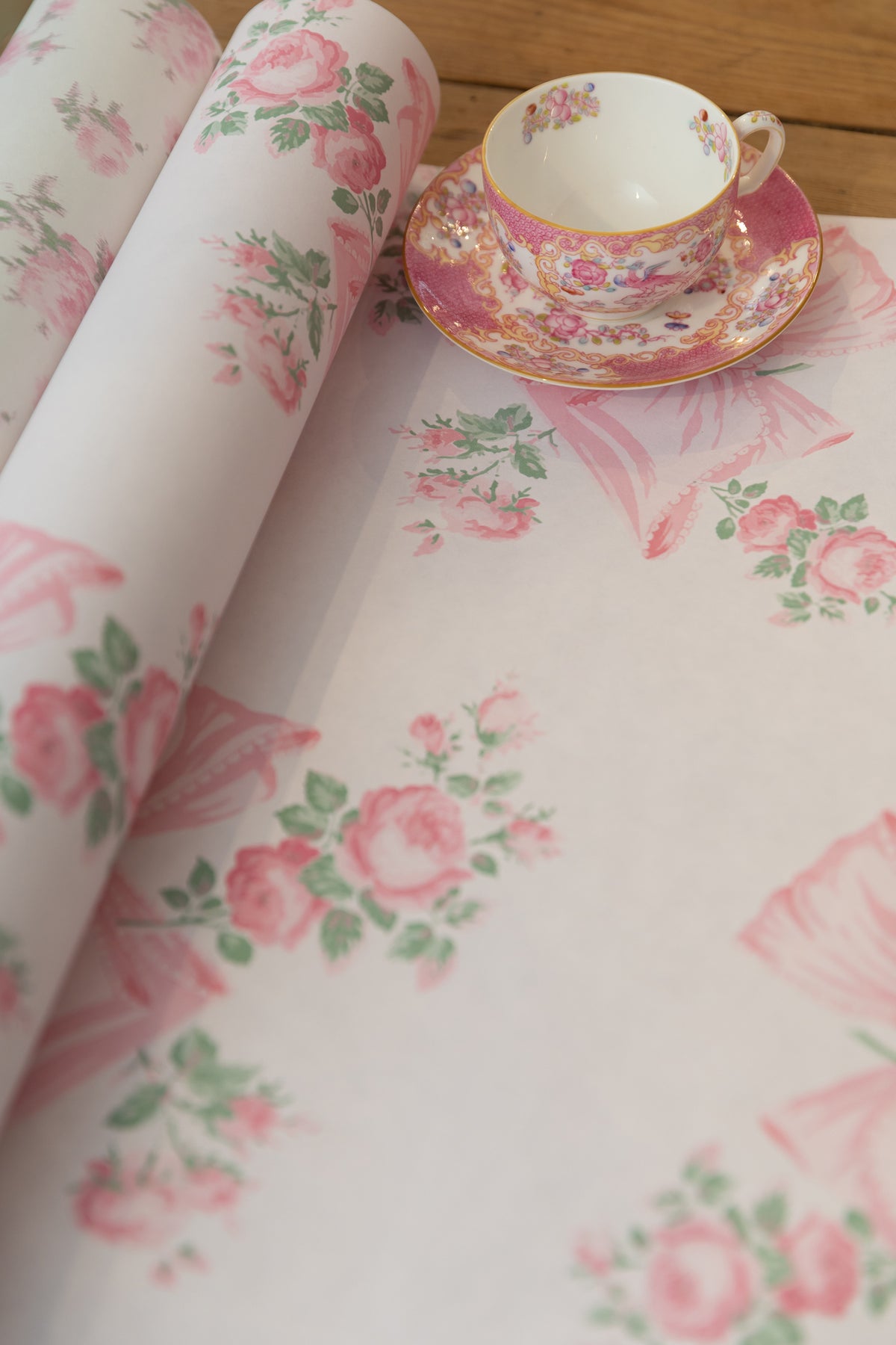Close-up of pink and mint floral wallpaper with roses and bow butterflies pattern