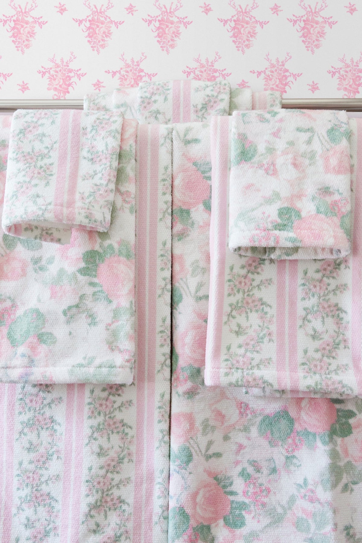 Wallpaper sample panels in pink and green floral print with vertical stripe accents