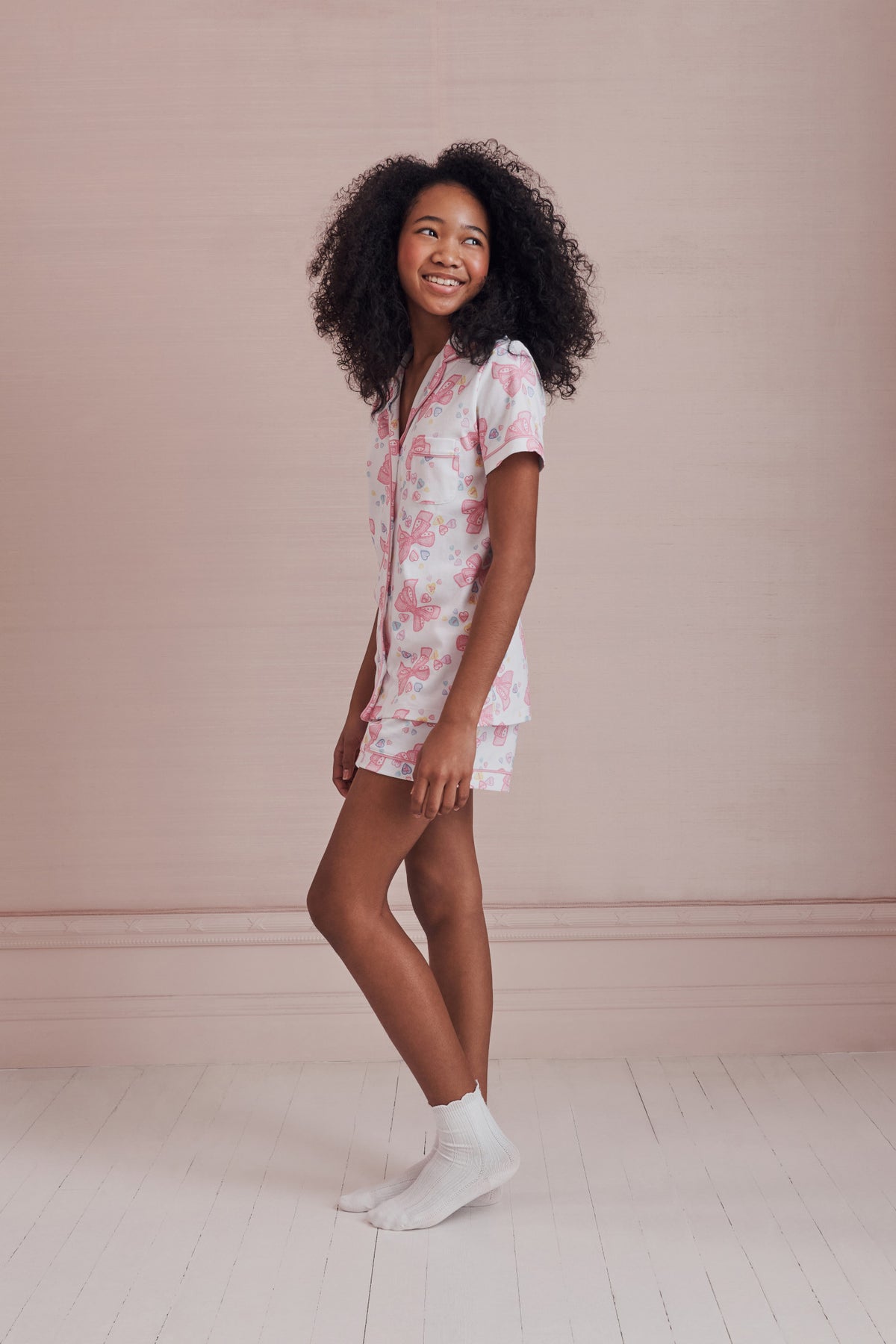 Women’s light pink bow print pajama set with polo top and matching shorts, side view
