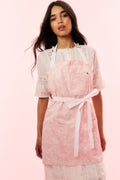 Perennial pink printed apron with waist tie and lace-trim bib, worn over white