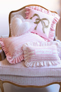 Pink decorative needlepoint pillow with ruffled trim, gold bow and heart design