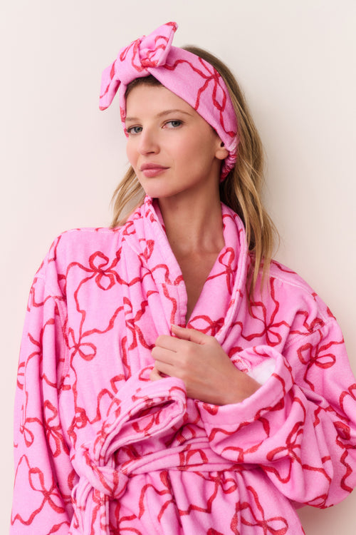 Pink bow print beauty headband with knotted bow, worn by model